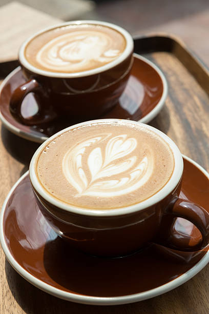 Two hot latte on wooden tray and table with selective focus on the latte art